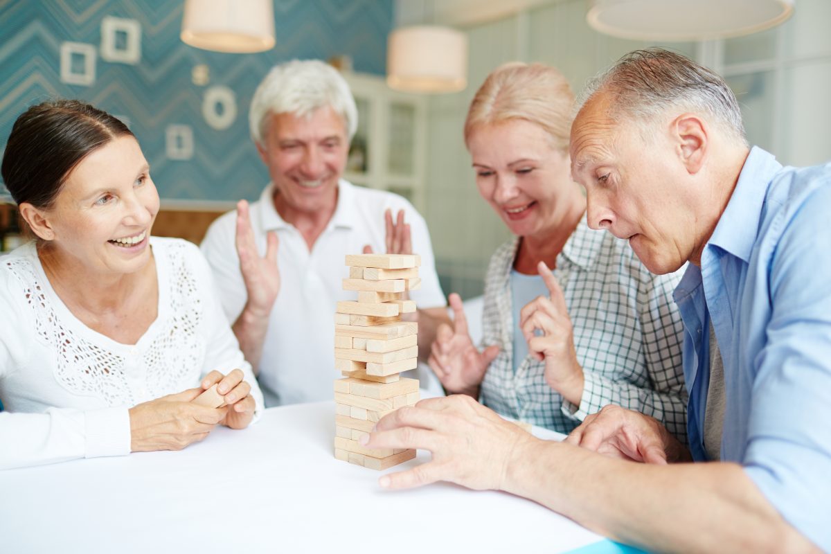 A group of seniors playing together and enjoying a game with wooden pieces.
