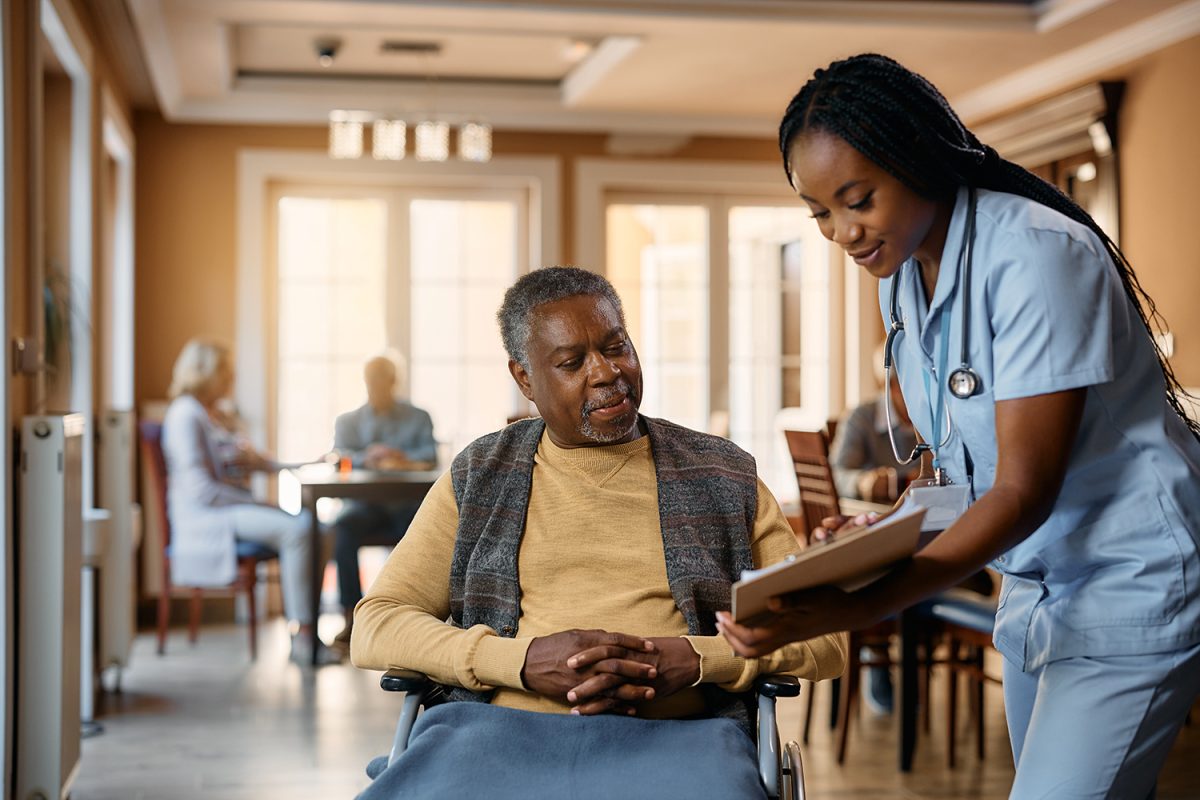 Senior man in wheelchair talking to nurse