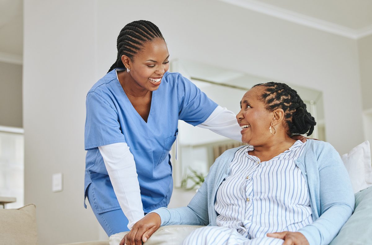 a caretaker laughing with a seated older woman